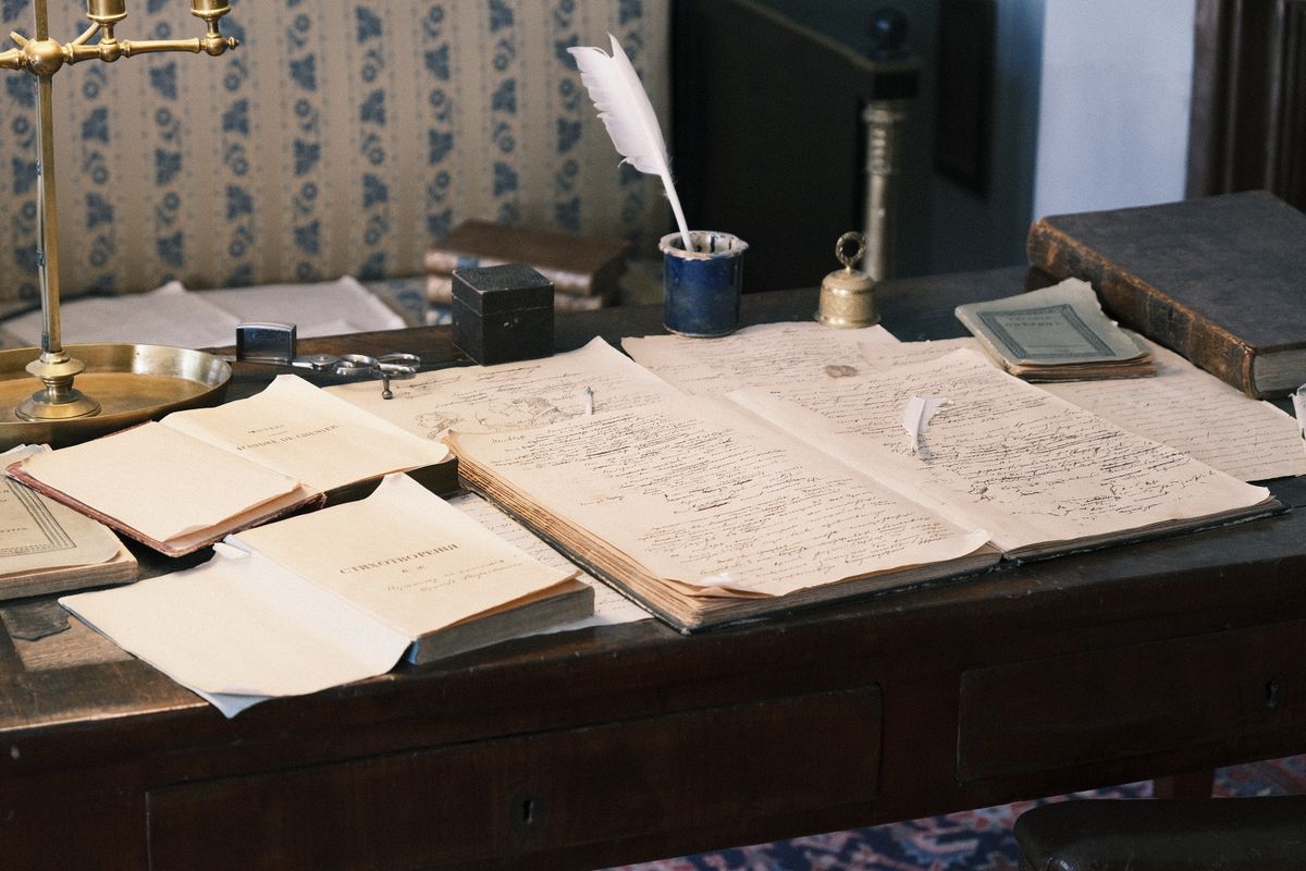 Open ledgers and hand-drawn plans on a draughtsman’s desk