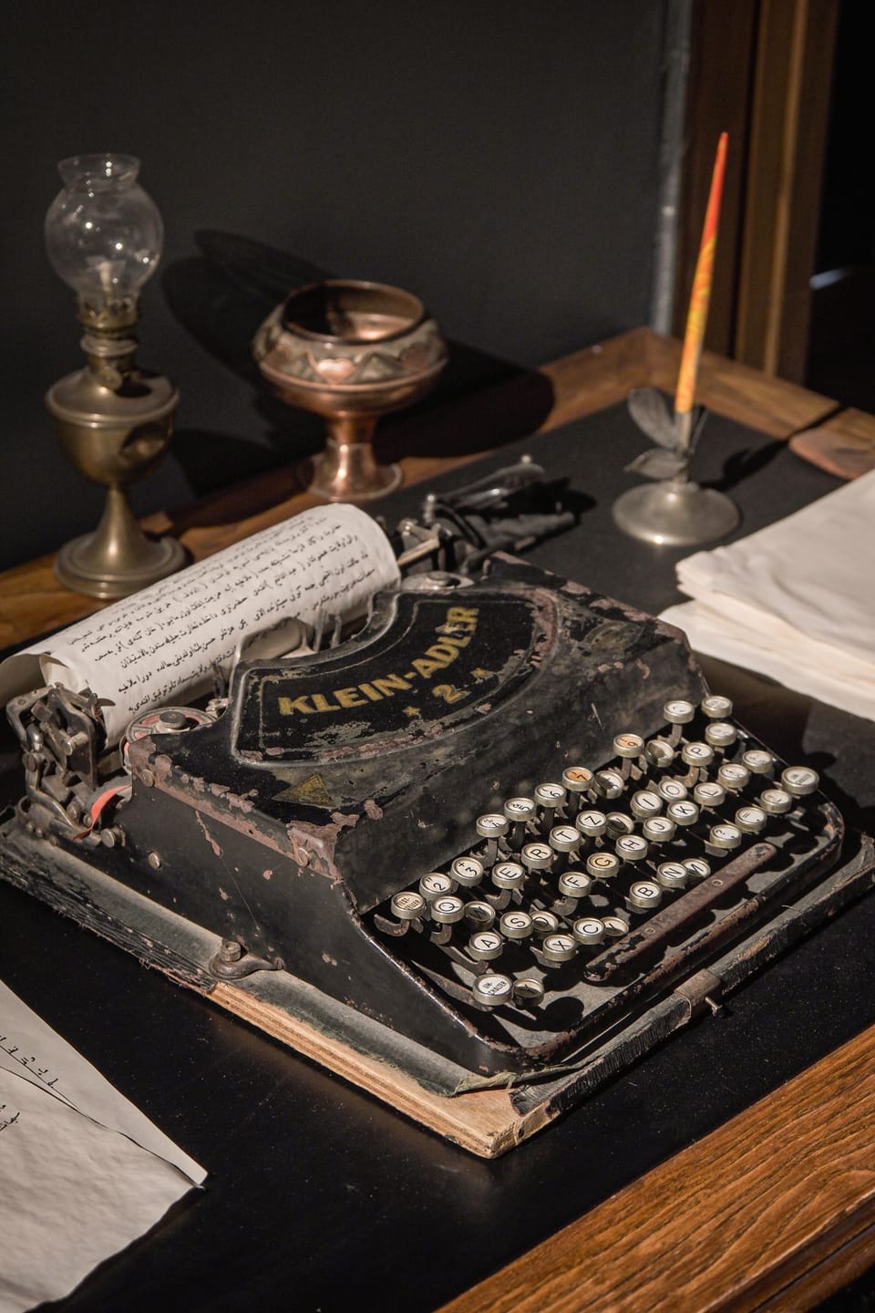 Antique typewriter beside a brass lamp and ink pen