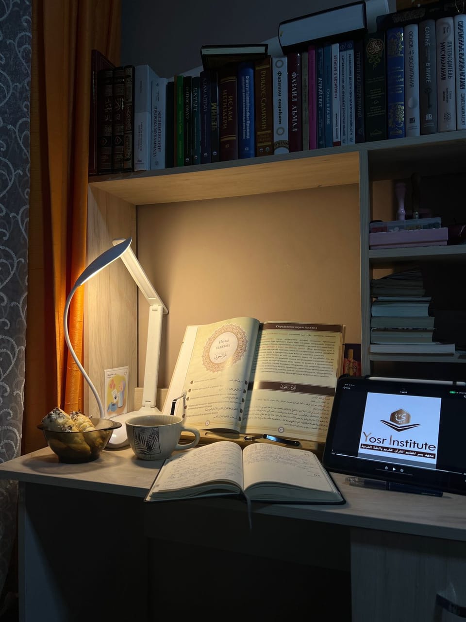Study desk with open books, tablet and a warm lamp