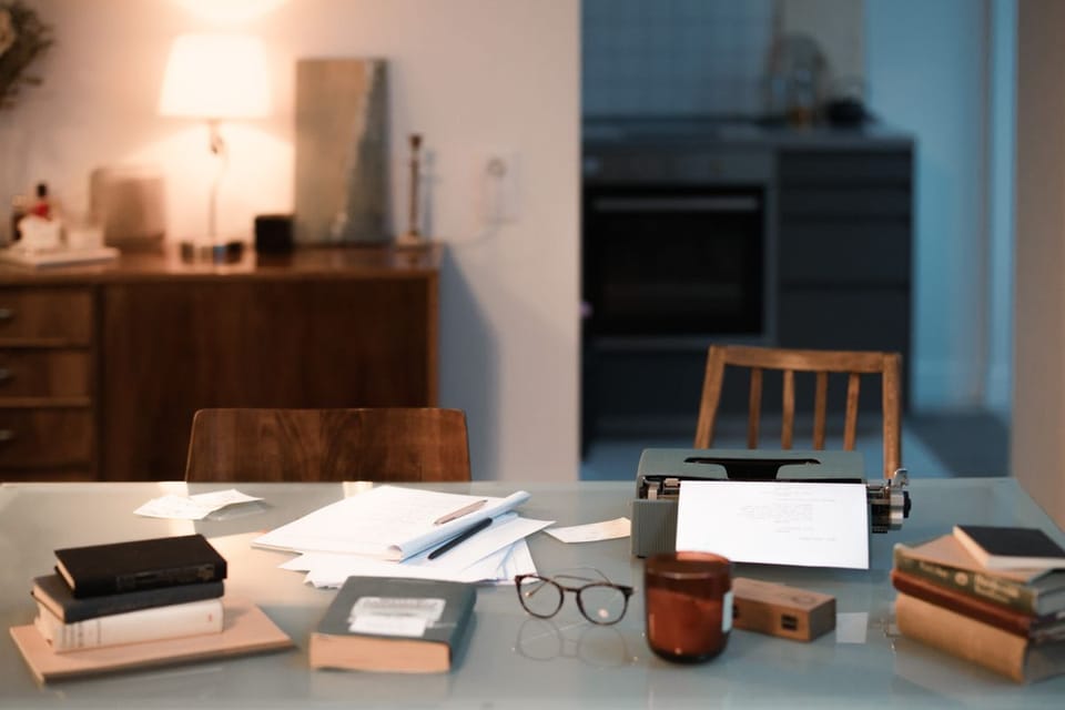 Home workspace with typewriter, books and warm lamp light